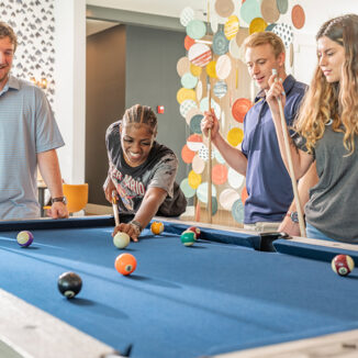 Group of young adults playing a game of pool