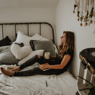 Young woman relaxing in bed while enjoying a cup of coffee